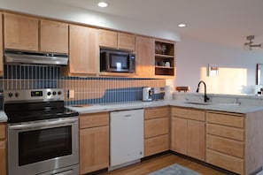 Una cocina moderna con armarios de madera, estufa de acero inoxidable, microondas y lavavajillas.
