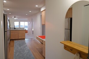 Une cuisine moderne avec des meubles en bois, un réfrigérateur en acier inoxydable et un tapis gris.