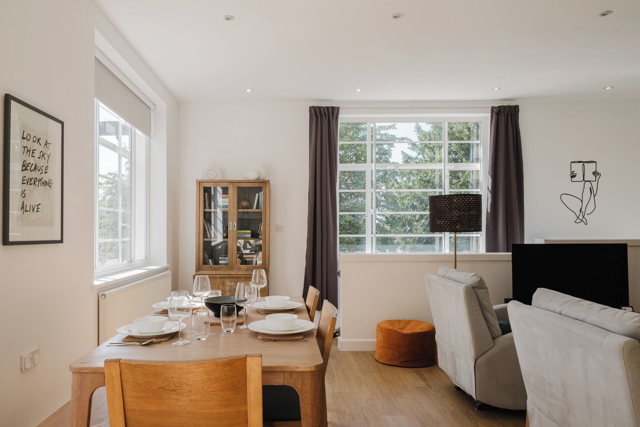 A modern living room with a dining area, large windows, and a cozy seating arrangement.