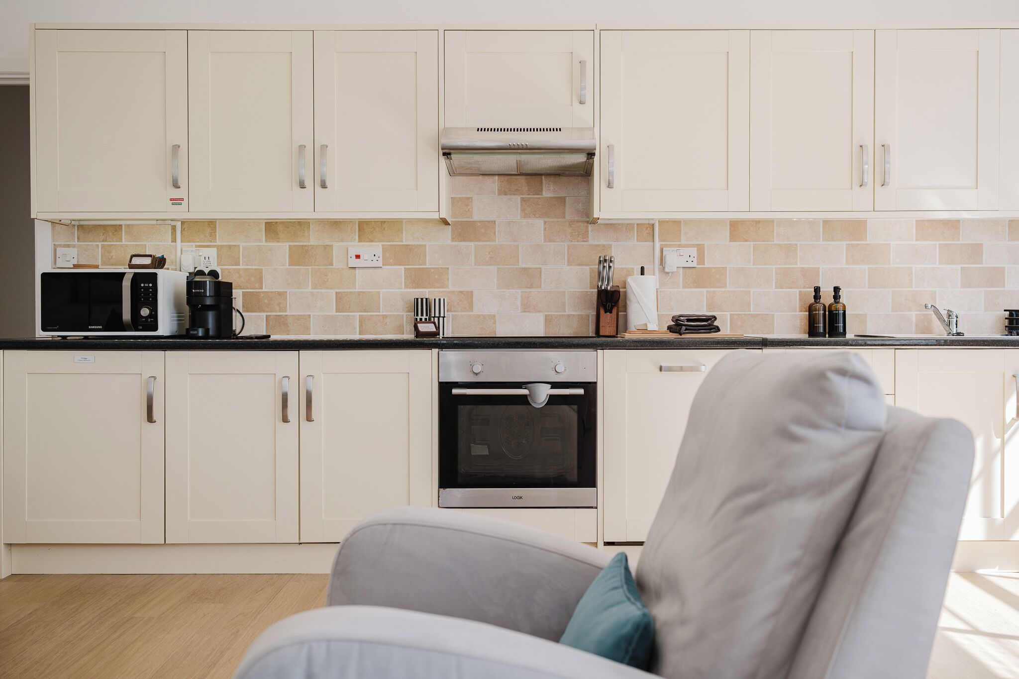 A modern kitchen with white cabinets, a microwave, a coffee maker, and a built-in oven.