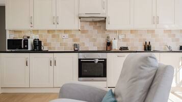A modern kitchen with white cabinets, a microwave, a coffee maker, and a built-in oven.