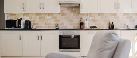 A modern kitchen with white cabinets, a microwave, a coffee maker, and a built-in oven.