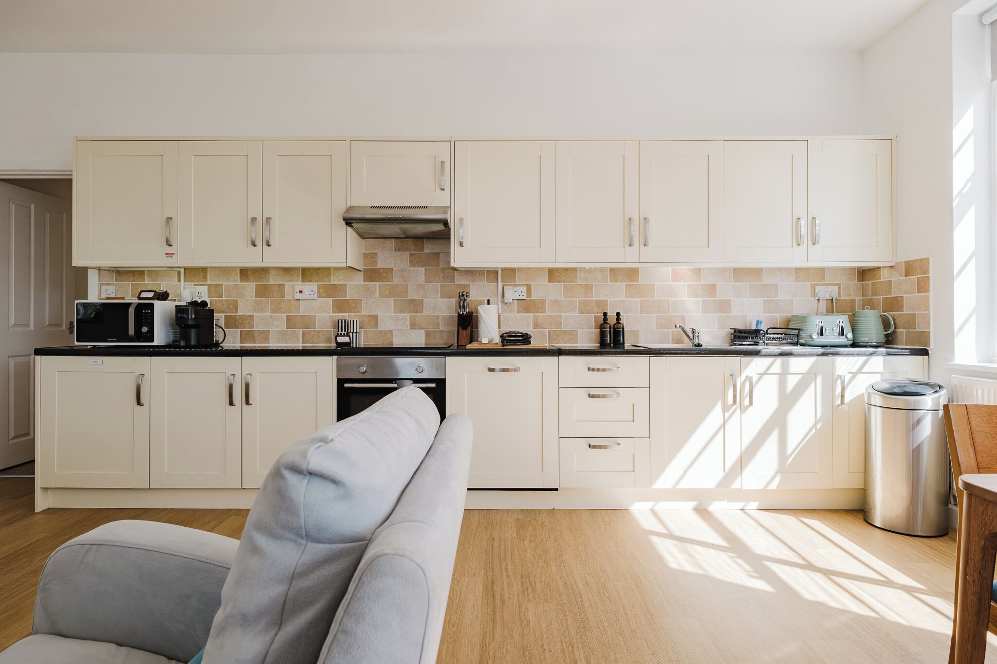 Una cocina moderna con armarios blancos, microondas, estufa y lavaplatos.