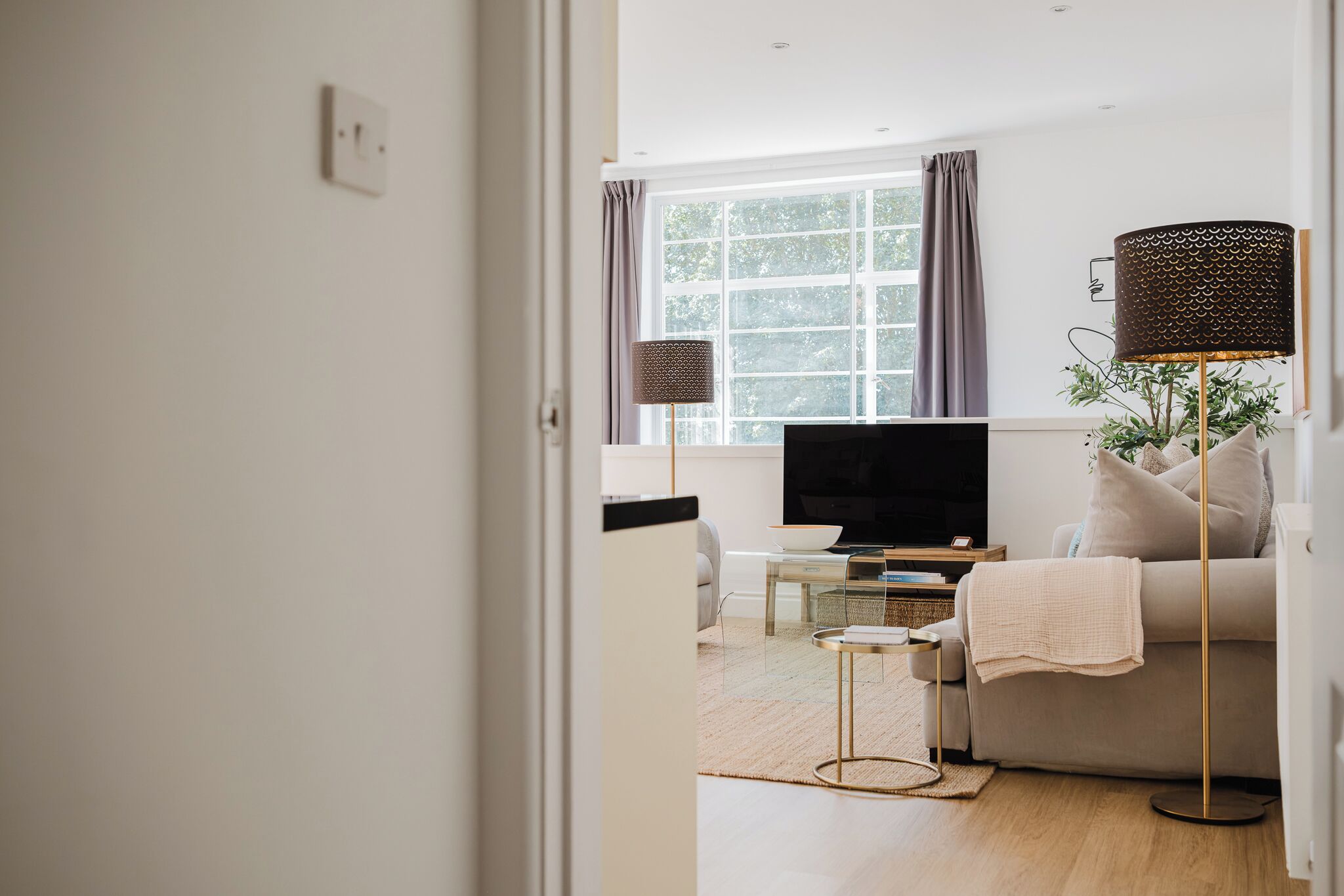 Uma sala de estar moderna com televisão, sofá e abajur.