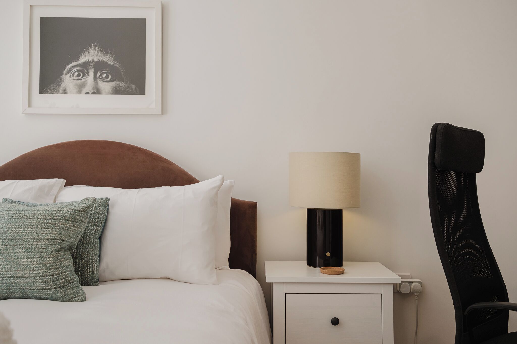 A hotel room with a bed, a nightstand, a lamp, and a chair.