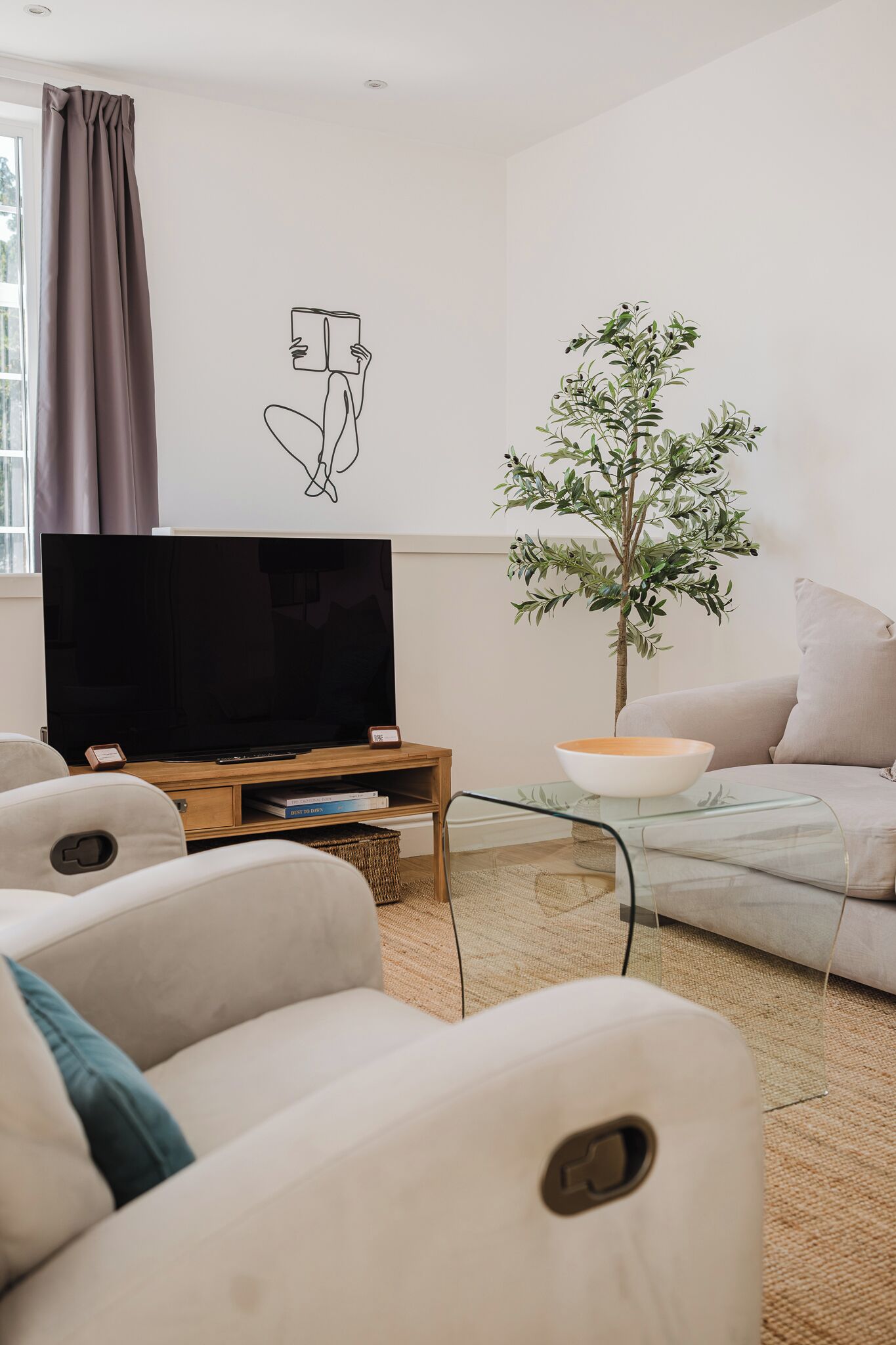 Un salon avec un téléviseur à écran plat posé sur un meuble en bois, un canapé, une table basse et un élément décoratif mural.