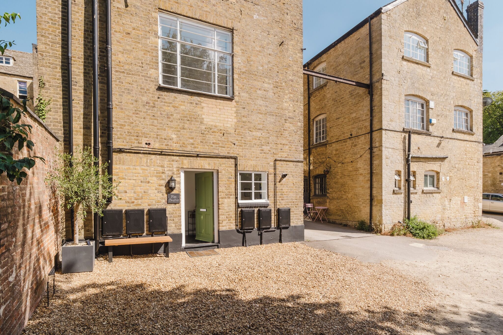 A brick building with a green door, a bench, and outdoor speakers.