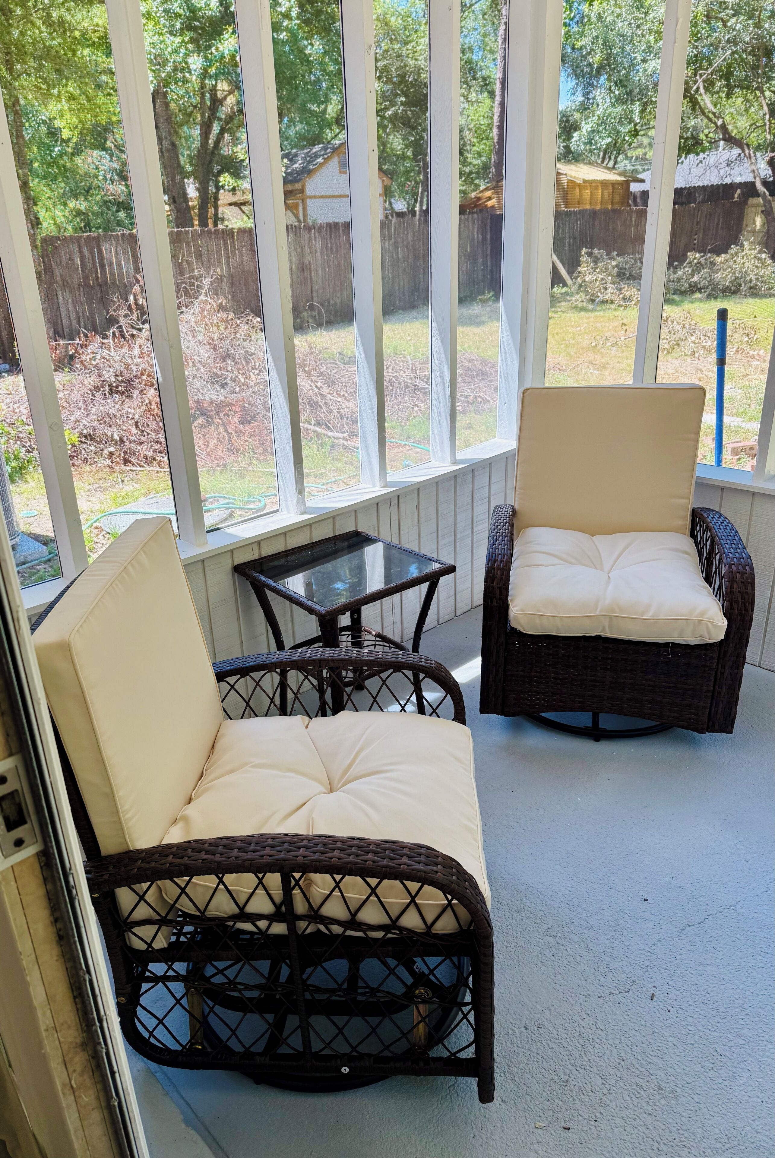 A covered patio area with wicker furniture and a glass-top table.