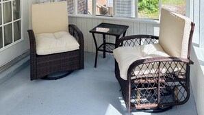 A covered patio with wicker furniture and a ceiling fan.