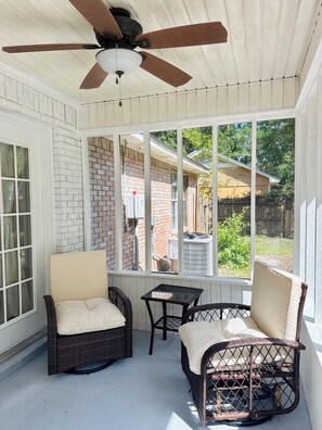 A covered patio with wicker furniture and a ceiling fan.