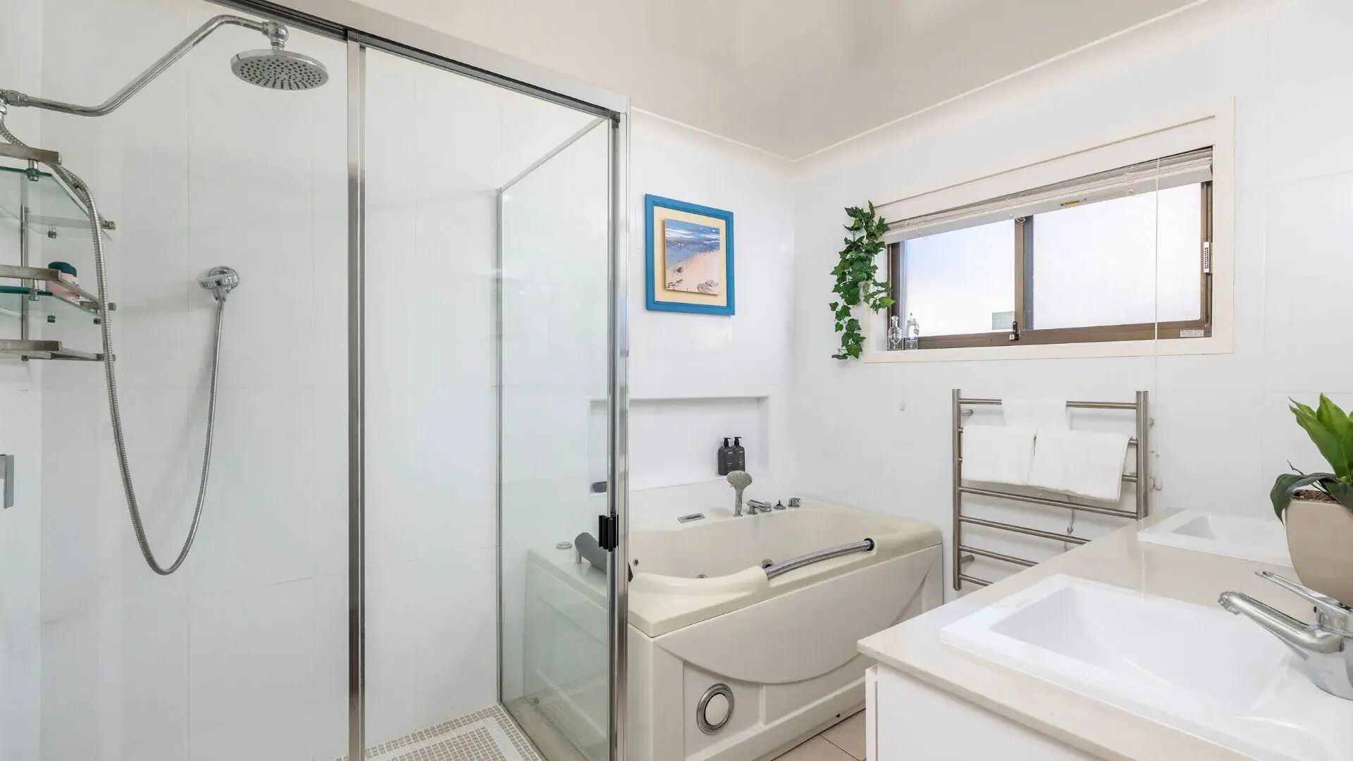 A modern bathroom with a glass-enclosed shower, a bathtub, and a sink area.