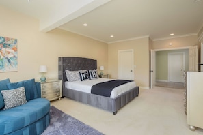 A bedroom with a large bed, a blue sofa, a nightstand, and a painting on the wall. - Main Home at Chateau Blanc 5 bedroom/pool/spa, fire pit, views! (Temecula)