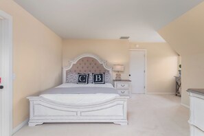 A bedroom with a bed, bedside tables, a door, and a small cabinet.