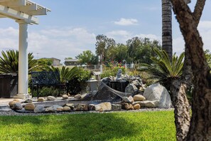 Un jardin aménagé avec un élément aquatique, des rochers et une pergola.