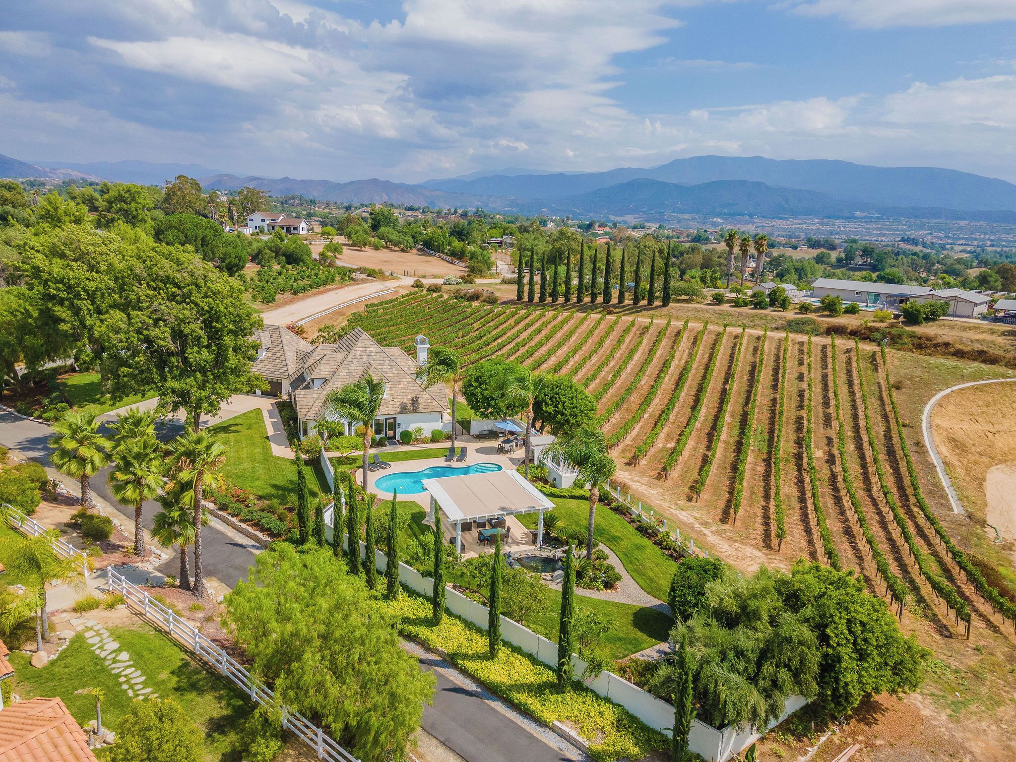 Une propriété résidentielle dotée d’une piscine, d’une pelouse bien entretenue et de rangées de vignes.