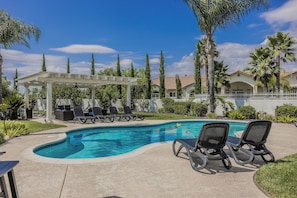 A swimming pool with lounge chairs, a pergola, and palm trees. - Spacious 5-bedroom in Temecula Wine Country w/Pool/Spa/Fire pit/View (Temecula)