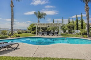 Une piscine avec des chaises longues et une pergola.