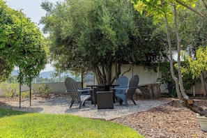 An outdoor seating area with a table and chairs, surrounded by trees and a view of the mountains. - Main Home at Chateau Blanc 5 bedroom/pool/spa, fire pit, views! (Temecula)