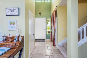 A hallway with a wooden desk, framed certificates, and a door leading to a room.