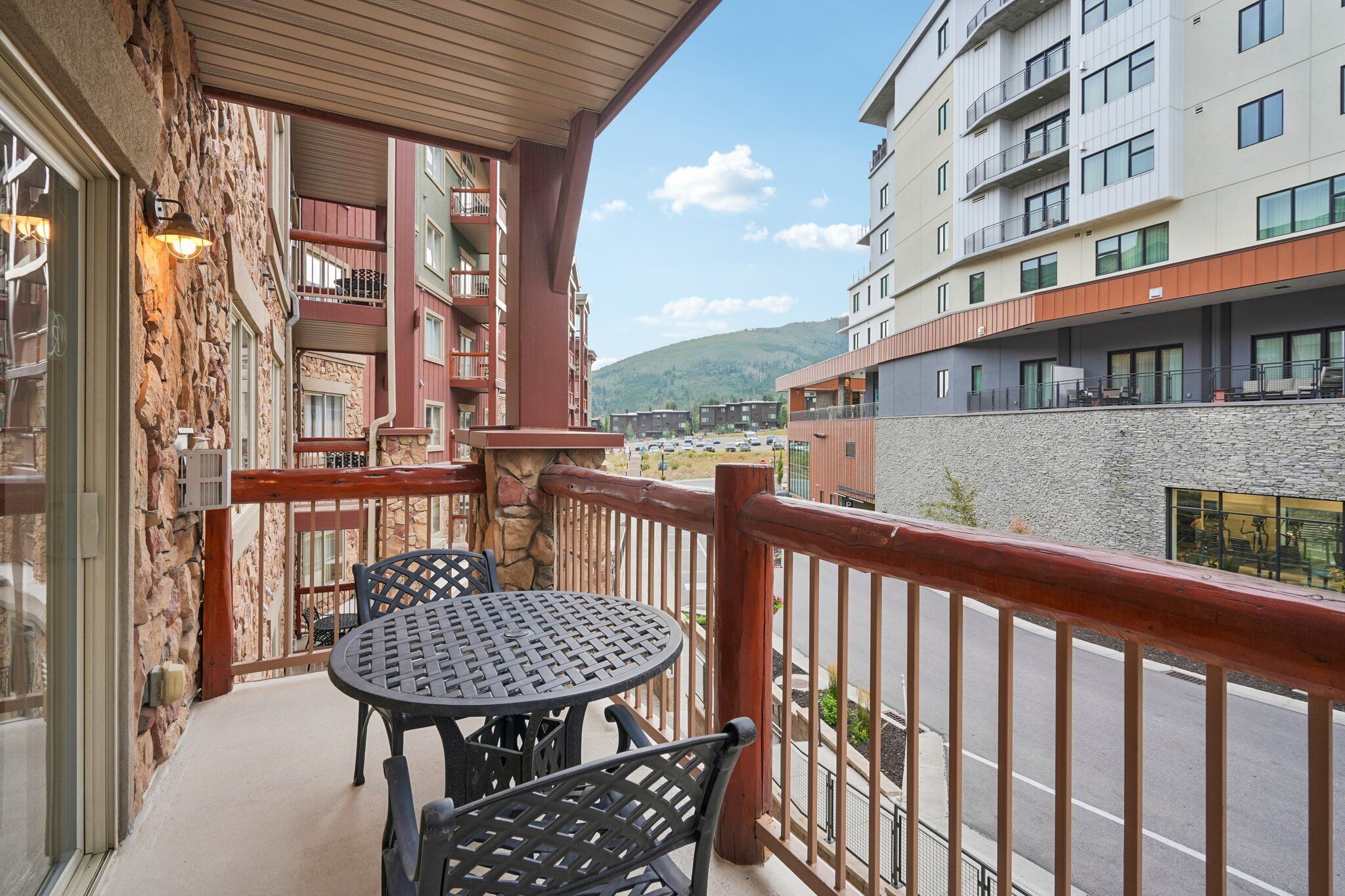 Un balcón con mesa y sillas, con vista a una calle y edificios.