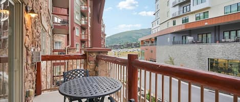 Un balcón con mesa y sillas, con vista a una calle y edificios.