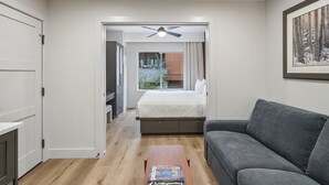 A modern bedroom with a bed, a grey sofa, a wooden coffee table, and a ceiling fan. - Westgate Studio | Ski-In/Ski-Out | Pools, Spa & Ski Valet (Park City)