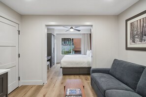 A modern bedroom with a bed, a grey sofa, a wooden coffee table, and a ceiling fan. - Westgate Studio | Ski-In/Ski-Out | Pools, Spa & Ski Valet (Park City)