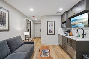 A modern living room with a gray sofa, a coffee table, and a TV in the background. - Westgate Studio | Ski-In/Ski-Out | Pools, Spa & Ski Valet (Park City)
