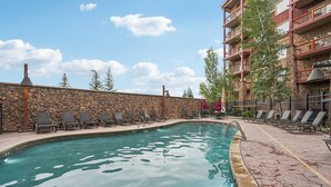 A swimming pool with lounge chairs and a stone wall. - Westgate Studio | Ski-In/Ski-Out | Pools, Spa & Ski Valet (Park City)