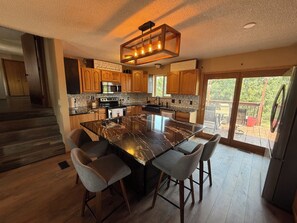 A modern kitchen with a large island, wooden cabinets, and a view to the outdoors.