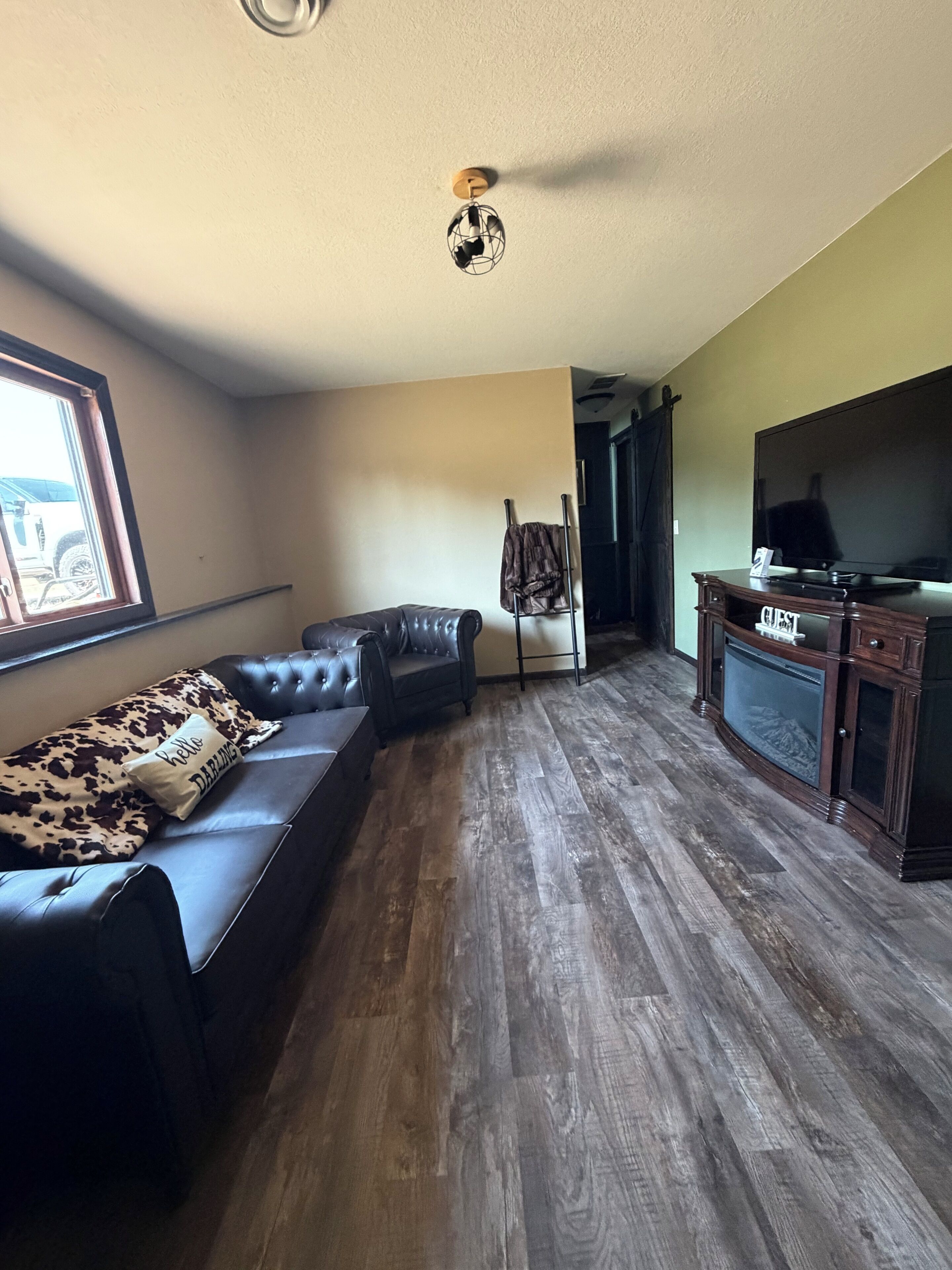 A living room with a leather sofa, a television, and a coat rack.