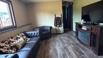 A living room with a leather sofa, a television, and a coat rack.