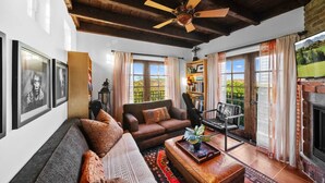 A living room with a sofa, armchair, and coffee table, a fireplace, and a ceiling fan. - Luxury Temecula Estate Pool Spa Views Theater (Temecula)