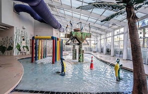 An indoor water play area with a slide, a water fountain, and a pool. - Oceanfront Dunes Village - Lazy River & Waterpark! (Myrtle Beach)