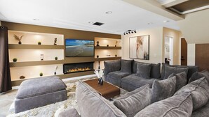 Uma sala de estar moderna com um sofá seccional, lareira, estantes embutidas e uma TV de tela plana.