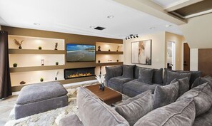 Ein modernes Wohnzimmer mit Ecksofa, Kamin, Einbauschränken und einem Flachbildfernseher.