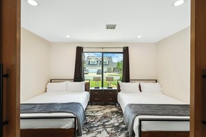 A bedroom with two beds, a large window with curtains, a ceiling light, and a view of a house outside. - Modern Luxury Designer Home (Midway City)