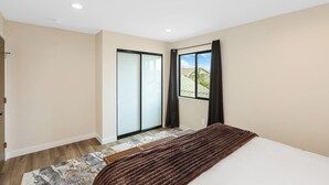 Quarto com cama, porta de correr de vidro e vista para o exterior.