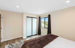 Ein Schlafzimmer mit einem Bett, einer Schiebetür und Blick ins Freie.