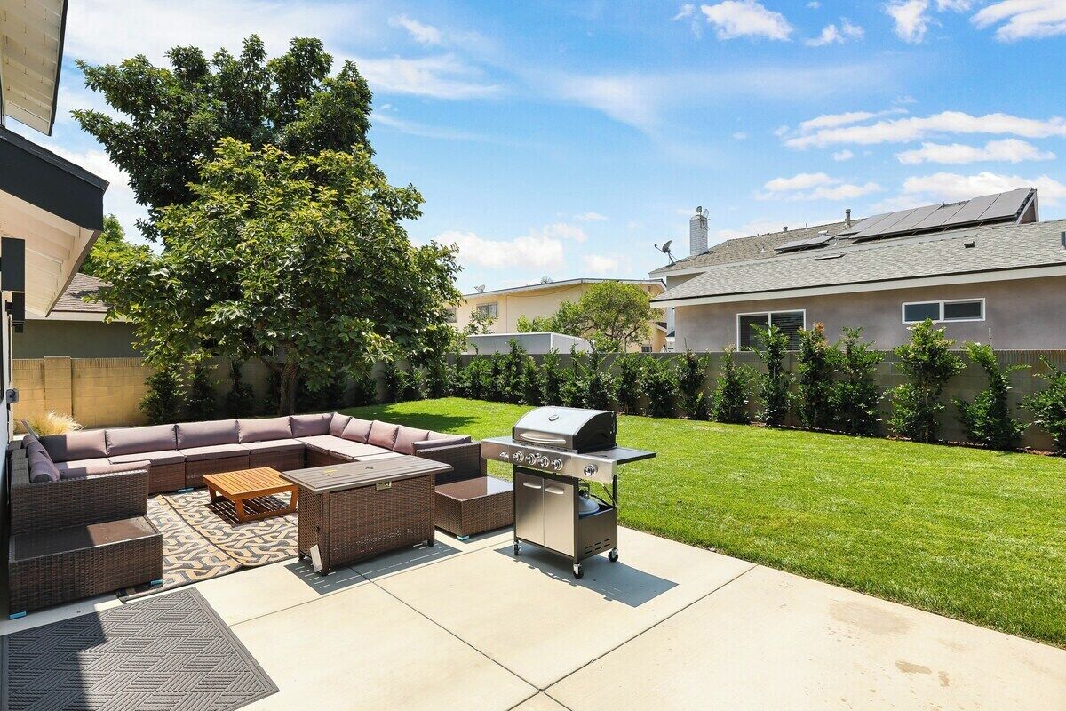 Une terrasse extérieure avec un canapé d’angle, un barbecue et une petite table.
