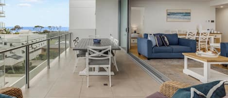 Un balcón con una mesa de comedor y sillas, un sofá y sillones de mimbre.
