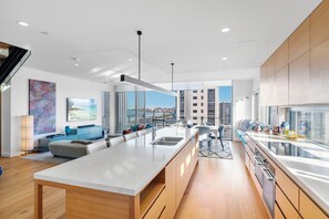A modern kitchen with a central island, a dining area with a view, and a living space with a sofa and artwork.