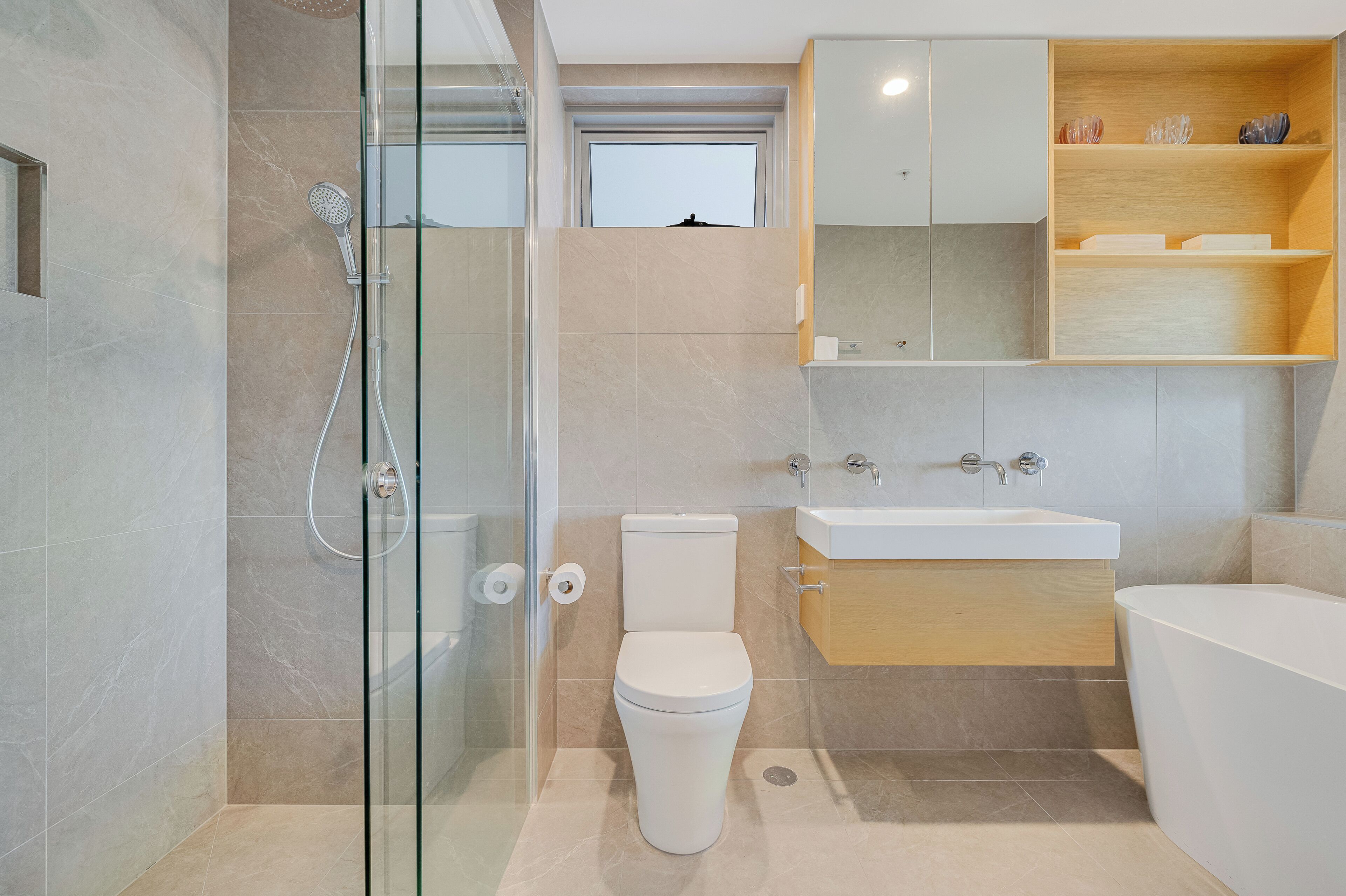 Un baño moderno con ducha envuelta en vidrio, inodoro, lavamanos y bañera.