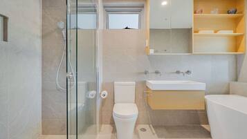 Un baño moderno con ducha envuelta en vidrio, inodoro, lavamanos y bañera.