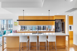 Una cocina moderna con una isla central, taburetes de bar, un refrigerador y vistas de la ciudad.