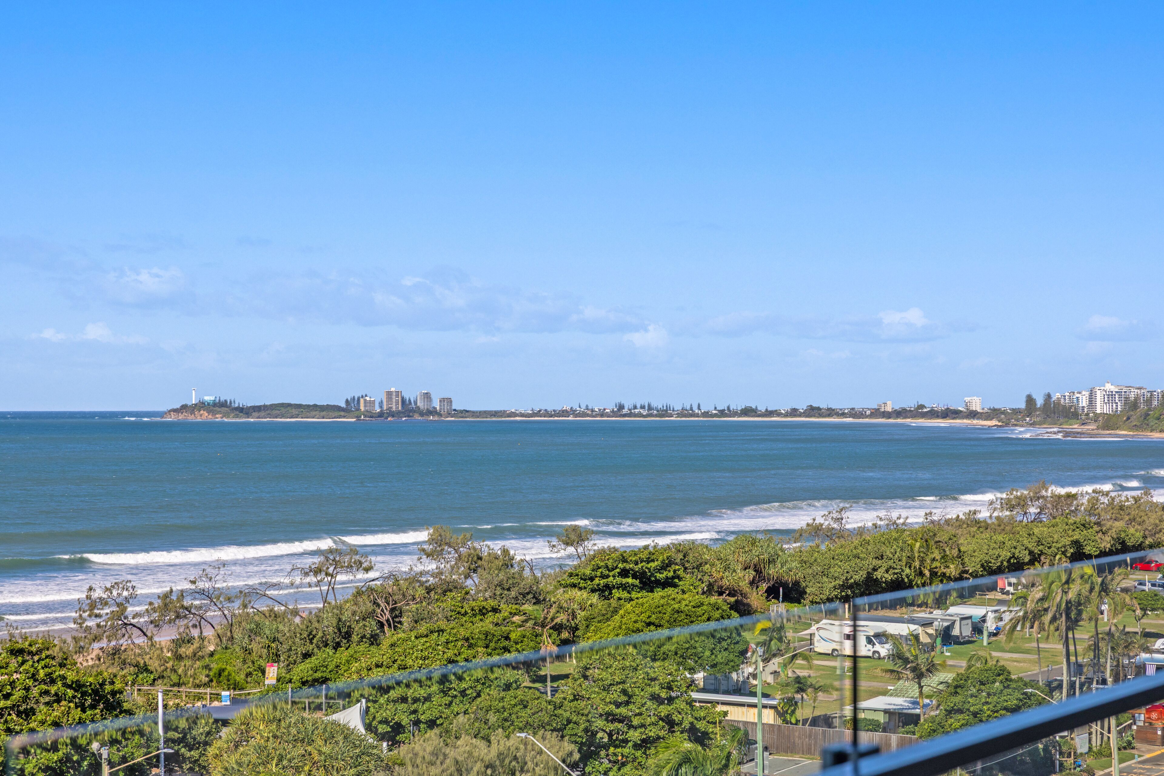 Vista costera con playa, océano y el perfil urbano a lo lejos.
