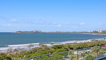 Vista costera con playa, océano y el perfil urbano a lo lejos.