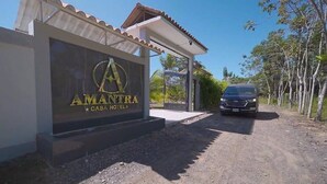 L’entrée d’un hôtel, avec une enseigne indiquant « AMANTRA CASA HOTEL » et un véhicule garé.