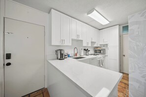 A modern kitchen with white cabinetry, a built-in oven, and a coffee maker. - Oceanfront 1BR, Waikīkī's Gold Coast, Diamond Head (Honolulu)