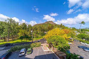 Ein Parkplatz mit mehreren Autos, im Hintergrund ein Berg und ein klarer Himmel.